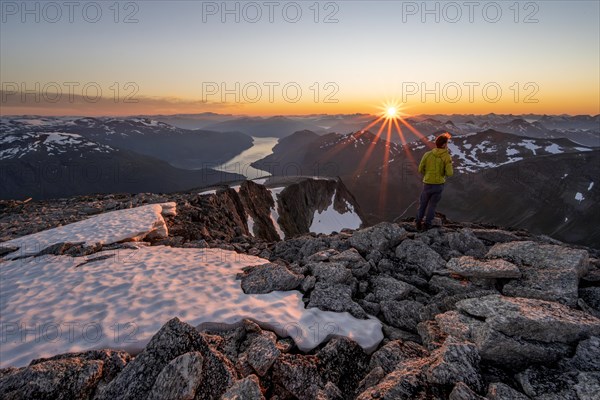 View of mountains and fjord Faleidfjorden, sun star at sunset, mountaineer at the summit of Skala,