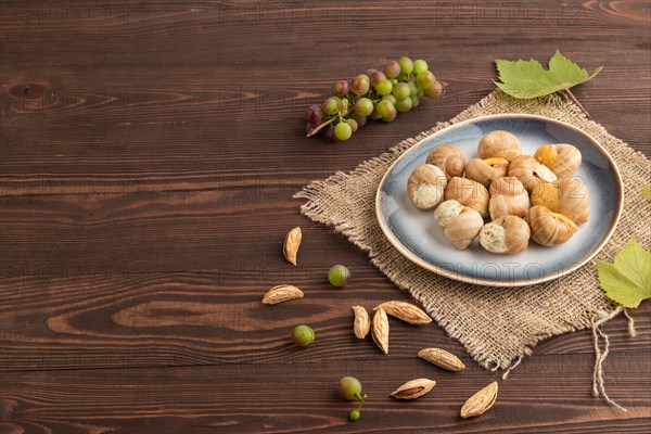 Grape (Burgundy) snails with butter and cheese on brown wooden background and linen textile. Side