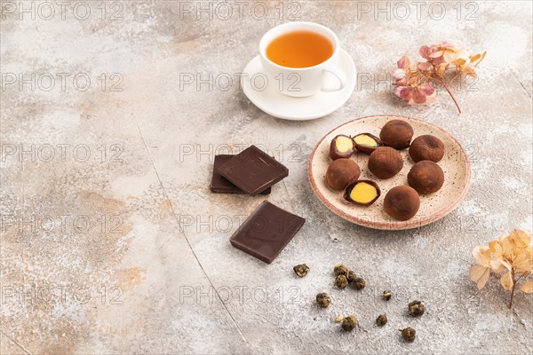 Japanese rice sweet buns chocolate mochi filled with cream and cup of green tea on brown concrete