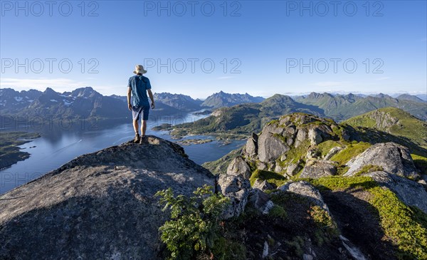 Mountaineer on the summit of Dronningsvarden or Stortinden, mountains and fjord Raftsund,