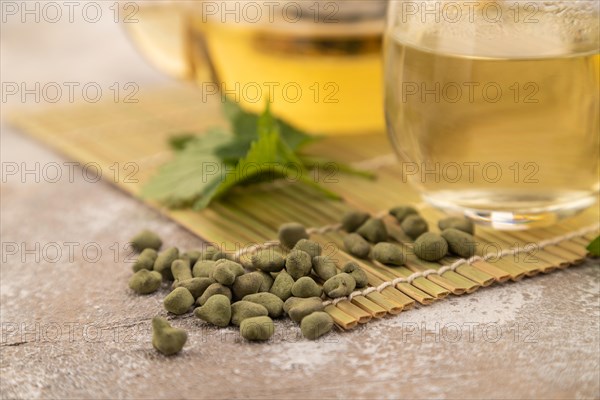 Green oolong tea with herbs in glass on brown concrete background. Healthy drink concept. Side