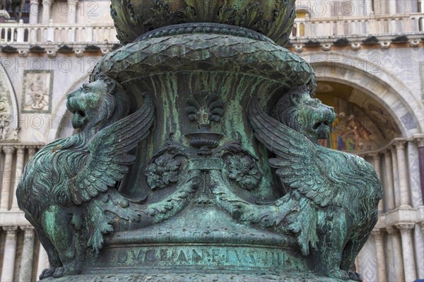 Old street ornament with winged lions and San Marco Basilica in the background, in St. Mark Square,