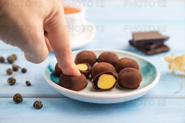 Japanese rice sweet buns chocolate mochi filled with cream and cup of green tea with hand on blue
