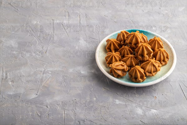 Homemade soft caramel fudge candies on blue plate on gray concrete background. side view, copy