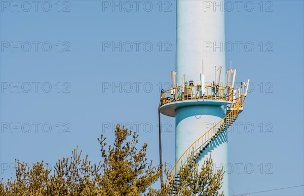Closeup of spiral staircase leading to cellphone transmission array on tall concrete column with