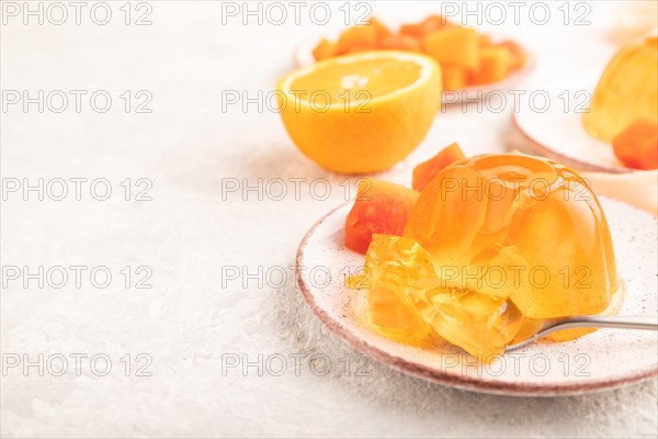 Papaya and orange jelly on gray concrete background and orange linen textile. side view, flat lay,