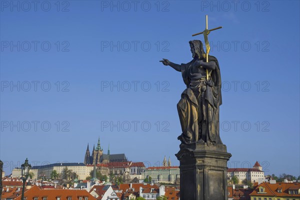 Statue of St. John the Baptist on Charles Bridge, with Hradcany castle and St. Vitus Cathedral in