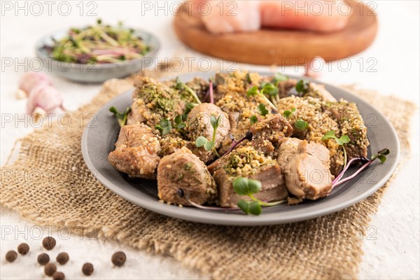 Stewed turkey fillet with garlic and sprouts of radish on white wooden background and linen textile