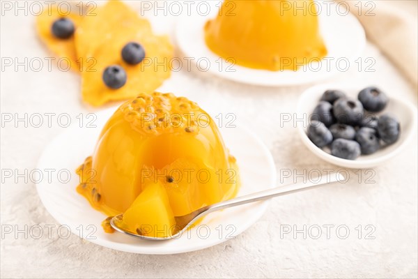 Mango and passion fruit jelly with blueberry on gray concrete background and linen textile. side