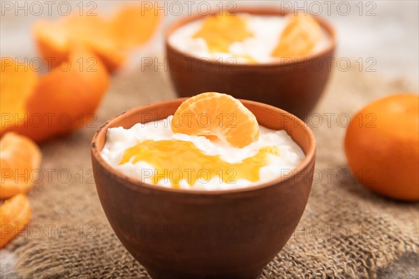 Grained cottage cheese with tangerine jam on brown concrete background and linen textile. side