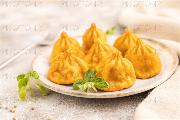 Fried manti dumplings with pepper, basil on gray concrete background and linen textile. Side view,