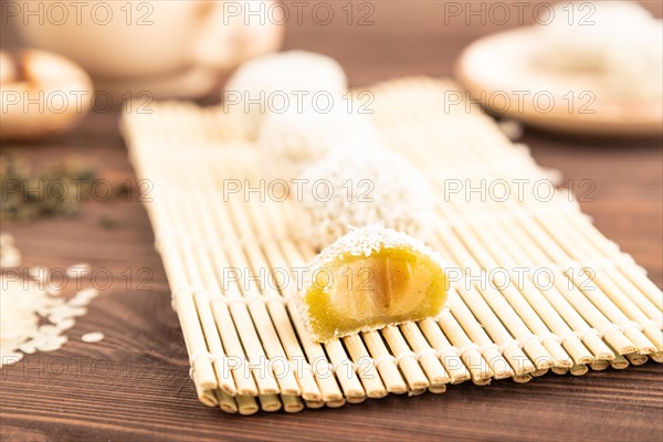 Japanese rice sweet buns mochi filled with pandan and coconut jam and cup of green tea on brown