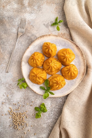 Fried manti dumplings with pepper, basil on gray concrete background and linen textile. Top view,