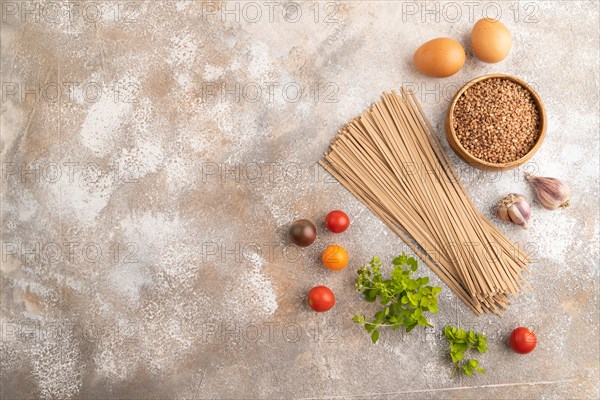 Japanese buckwheat soba noodles with tomato, eggs, spices, herbs on brown concrete background. Top