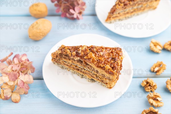Walnut and hazelnut cake with caramel cream, cup of coffee on blue wooden background. side view,