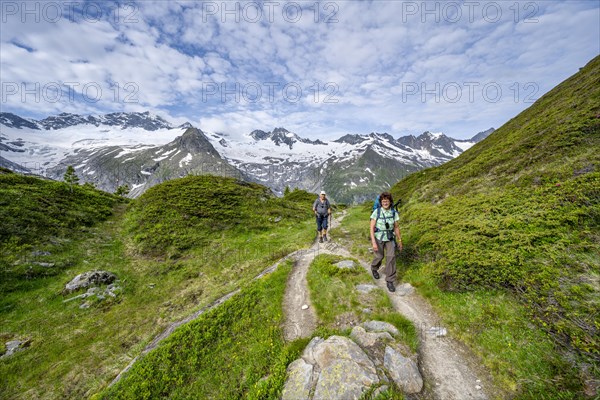 Two mountaineers on a hiking trail in a picturesque mountain landscape, mountain peaks with snow