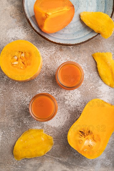 Baby puree with fruits mix, pumpkin, persimmon, mango infant formula in glass jar on brown concrete