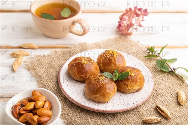 Homemade traditional turkish dessert sekerpare with almonds and honey, cup of green tea on white