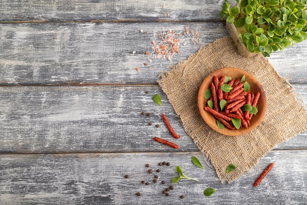 Small smoked sausage with borage microgreen, salt and pepper on gray wooden background and linen