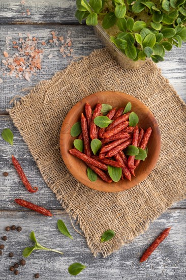 Small smoked sausage with borage microgreen, salt and pepper on gray wooden background and linen
