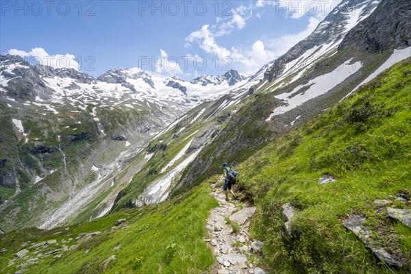 Mountaineer on hiking trail in picturesque mountain landscape, in the background mountain peak