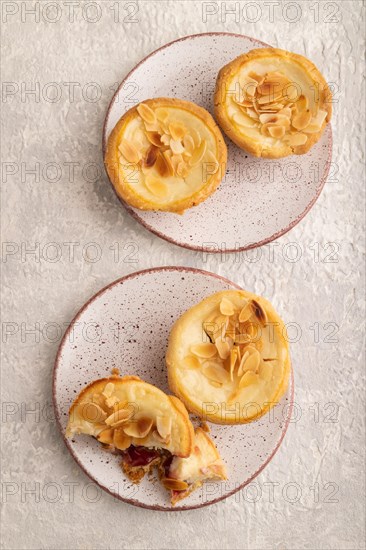 Traditional portuguese cakes pasteis de nata, custard small pies with almonds on gray concrete