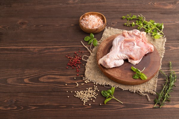 Raw turkey wing with herbs and spices on a wooden cutting board on a brown wooden background and