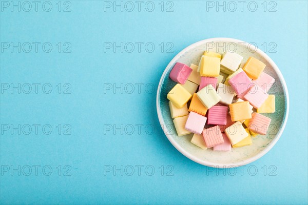 Various fruit jelly chewing candies on plate on blue pastel background. apple, banana, tangerine,