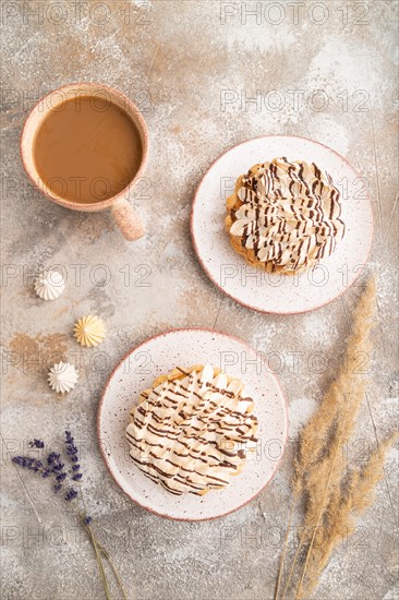 Two tartlets with meringue cream and cup of coffee on brown concrete background. top view, flat lay