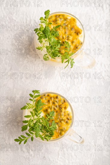 Yogurt with passionfruit and marigold microgreen in glass on gray concrete background. Top view,