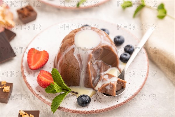 Chocolate jelly with strawberry, blueberry and milk cream sliced with spoon on gray concrete