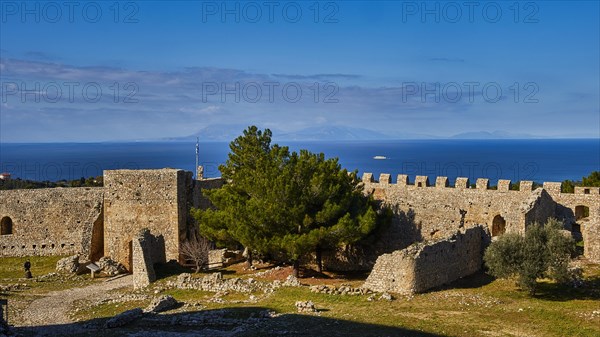 Sunny view of an old fortress with green trees and a blue sky with light clouds, Chlemoutsi, High