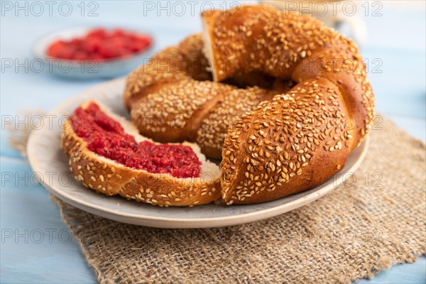 Homemade sweet bun with raspberry jam and cup of coffee on a blue wooden background and linen