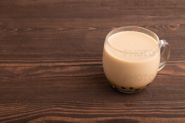 Bubble tea with pistachio and caramel in glass on brown wooden background. Healthy drink concept.