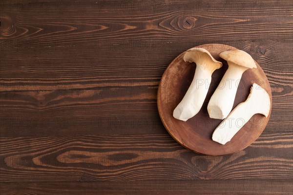 King Oyster mushrooms or Eringi (Pleurotus eryngii) on brown wooden background. Top view, flat lay,