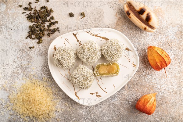 Japanese rice sweet buns mochi filled with pandan jam and cup of green tea on brown concrete