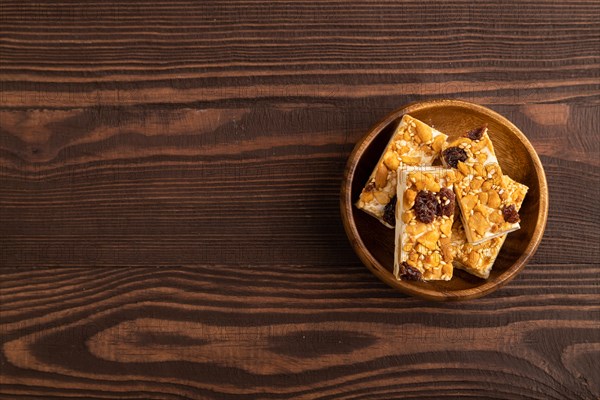 Traditional candy nougat with nuts and sesame on brown wooden background. top view, flat lay, copy