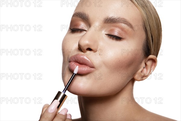 Beauty portrait of model with natural make-up holding a jar of cream. Fashion shiny highlighter on