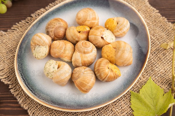 Grape (Burgundy) snails with butter and cheese on brown wooden background and linen textile. Side