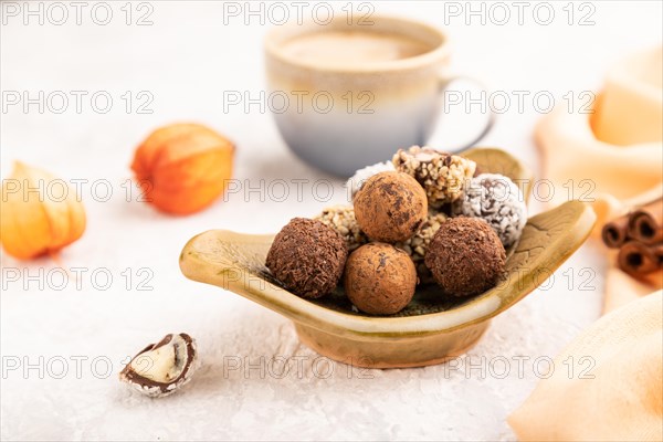 Chocolate truffle candies with cup of coffee on a gray concrete background and orange textile. side