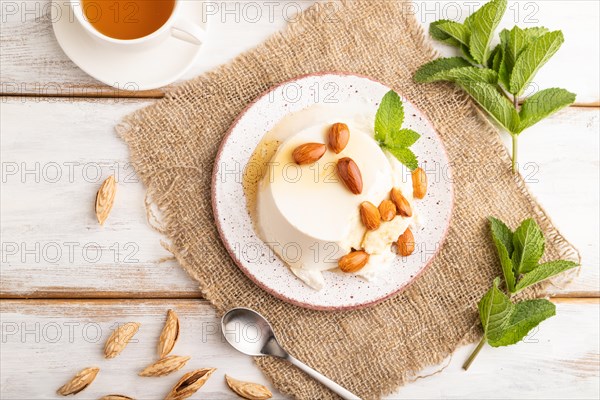 Ricotta cheese with honey and almonds on white wooden background and linen textile. top view, flat