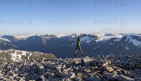 Mountain panorama with mountain peaks and glacier Jostedalsbreen, mountaineer stretches his arms in