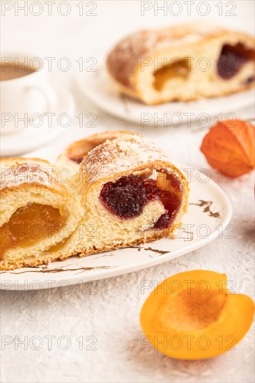 Homemade sweet bun with apricot jam and cup of coffee on gray concrete background. side view, close