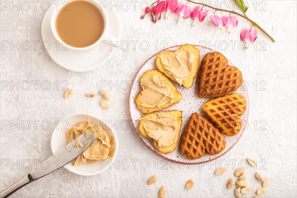 Homemade waffle with peanut butter and cup of coffee on a gray concrete background. top view, flat