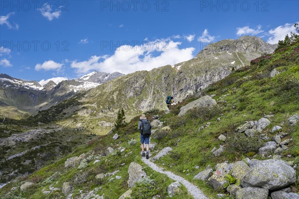 Mountaineers on a hiking trail in front of a picturesque mountain landscape, rocky mountain peaks