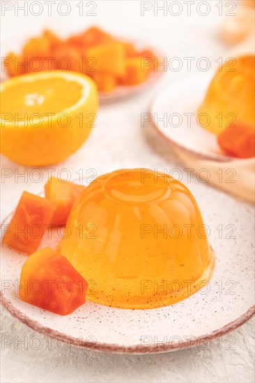 Papaya and orange jelly on gray concrete background and orange linen textile. side view, flat lay,