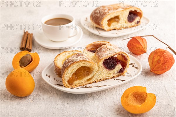 Homemade sweet bun with apricot jam and cup of coffee on gray concrete background. side view, close