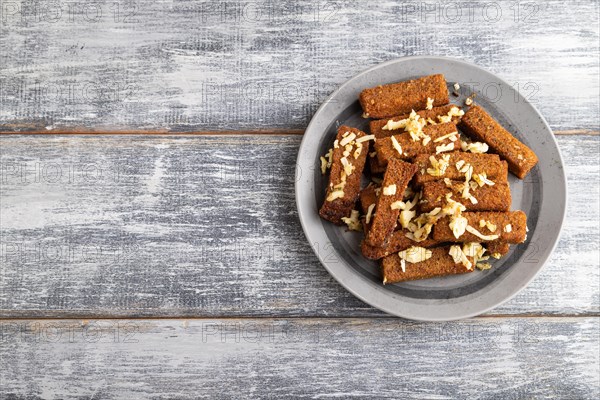 Cheese and toast on a gray plate on a gray wooden background. Top view, flat lay, close up, copy