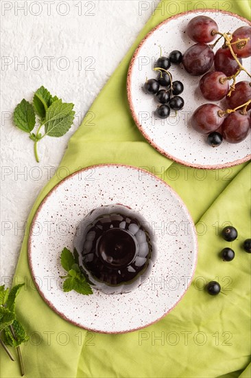 Black currant and grapes jelly on gray concrete background and green linen textile. top view, flat