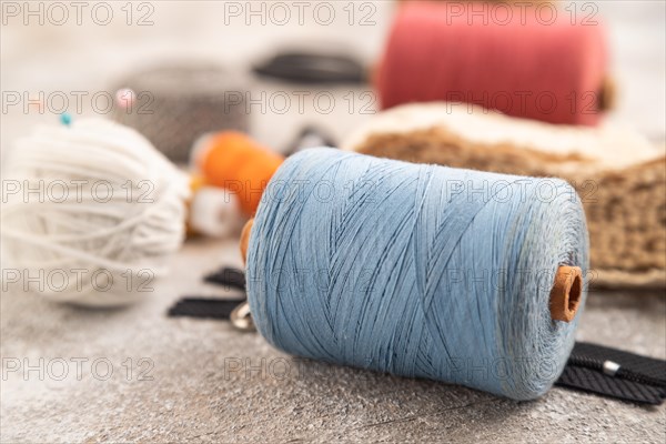 Sewing accessories: scissors, thread, thimbles, braid on brown concrete background. Side view,